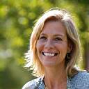 Smiling woman in her early 40s, Sarah, looking vibrant and healthy, possibly outside in a park, showing her transformation.